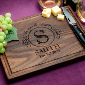 walnut cutting board wit cheese green grapes and two glasses of white wine