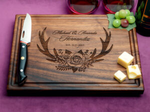 walnut charcuterie board with cheeses green grapes cheese knife and two glasses of red wine on purple background