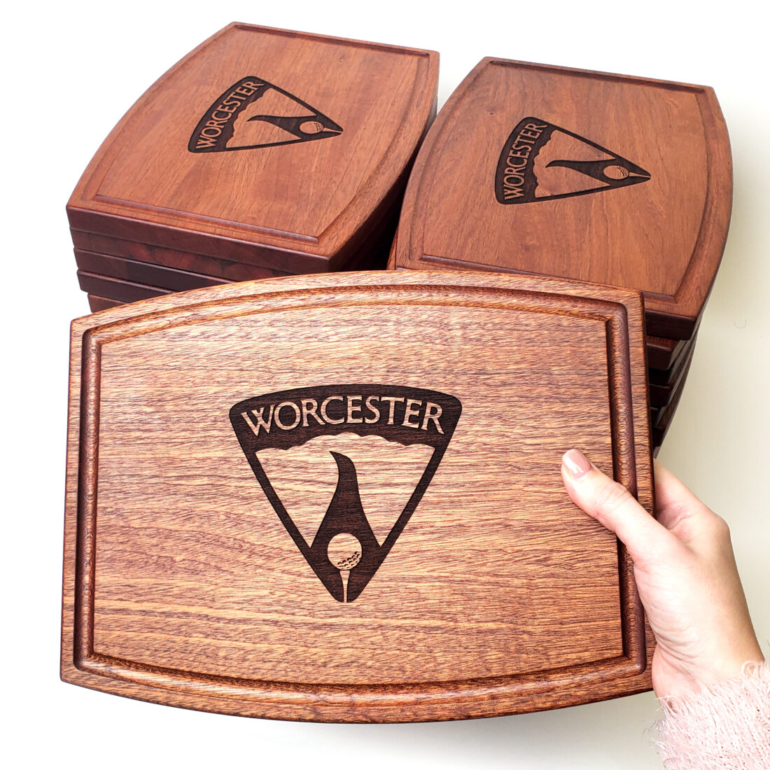 Personalized mahogany cutting board engraved with the 'Worcester' logo, crafted for a golf club event. These boards, intended as thoughtful appreciation gifts for members, showcase exquisite wood and individualized craftsmanship