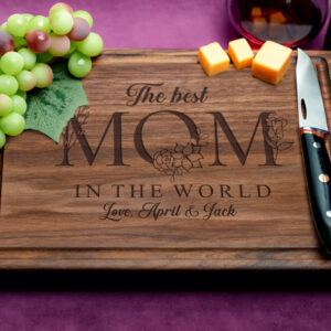 Custom walnut cutting board featuring a juice groove and engraved with the heartfelt message 'The best mom in the world'. The dark wood grain enhances the elegant look, showcasing skilled craftsmanship and thoughtful design for a perfect Mother's Day gift.