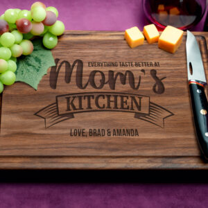 A personalized walnut cutting board with a juice groove, engraved with 'Everything Tastes Better at Mom's Kitchen'. This heartfelt design creates a lasting memory, making it the perfect gift to cherish and celebrate the love and warmth of mom's kitchen.