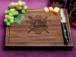 Elegant walnut cutting board adorned with 'Dad the grill master' inscription, showcasing meticulous craftsmanship and a convenient juice groove. Crafted from premium walnut wood, the board combines durability with aesthetic appeal, making it a perfect gift for barbecue aficionados.