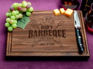 Celebrate Dad's culinary passion with our custom walnut cutting board, showcasing a unique 'Dad's Barbeque Best In Town' engraving and an efficient juice groove. Engineered for both style and durability, it's an exceptional gift choice for Father's Day and beyond. Crafted from premium walnut, this board exudes natural elegance and features antimicrobial properties, promoting a clean kitchen environment. Whether used for food prep or presentation, its thoughtful design ensures practicality and sentimentality, making it a cherished addition to any chef's collection.