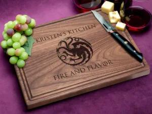 Fire and flavor cutting board with knife cheese wine and grapes on purple background