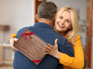 Smiling woman hugging a man, holding gift personalized engraved cutting board