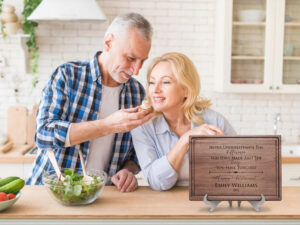 Senior couple in the kitchen, happy, enjoying salad, displaying a retirement gift.