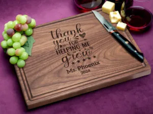 Teacher appreciation gift on purple background with knife, cheese and grapes