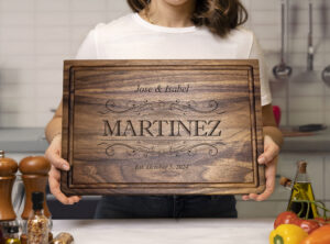 woman holding engraved chopping block in the kitchen with spices vegetables and olive oil