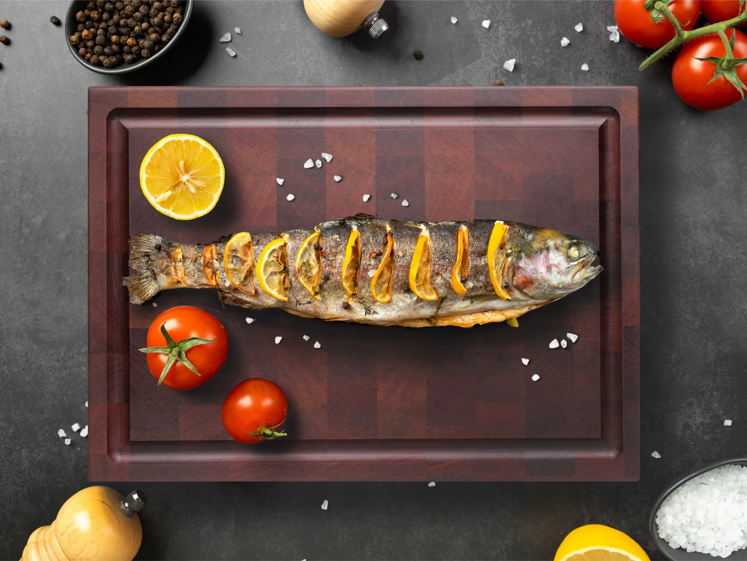 fried fish on mahogany wood end grain block with lemon and tomatos